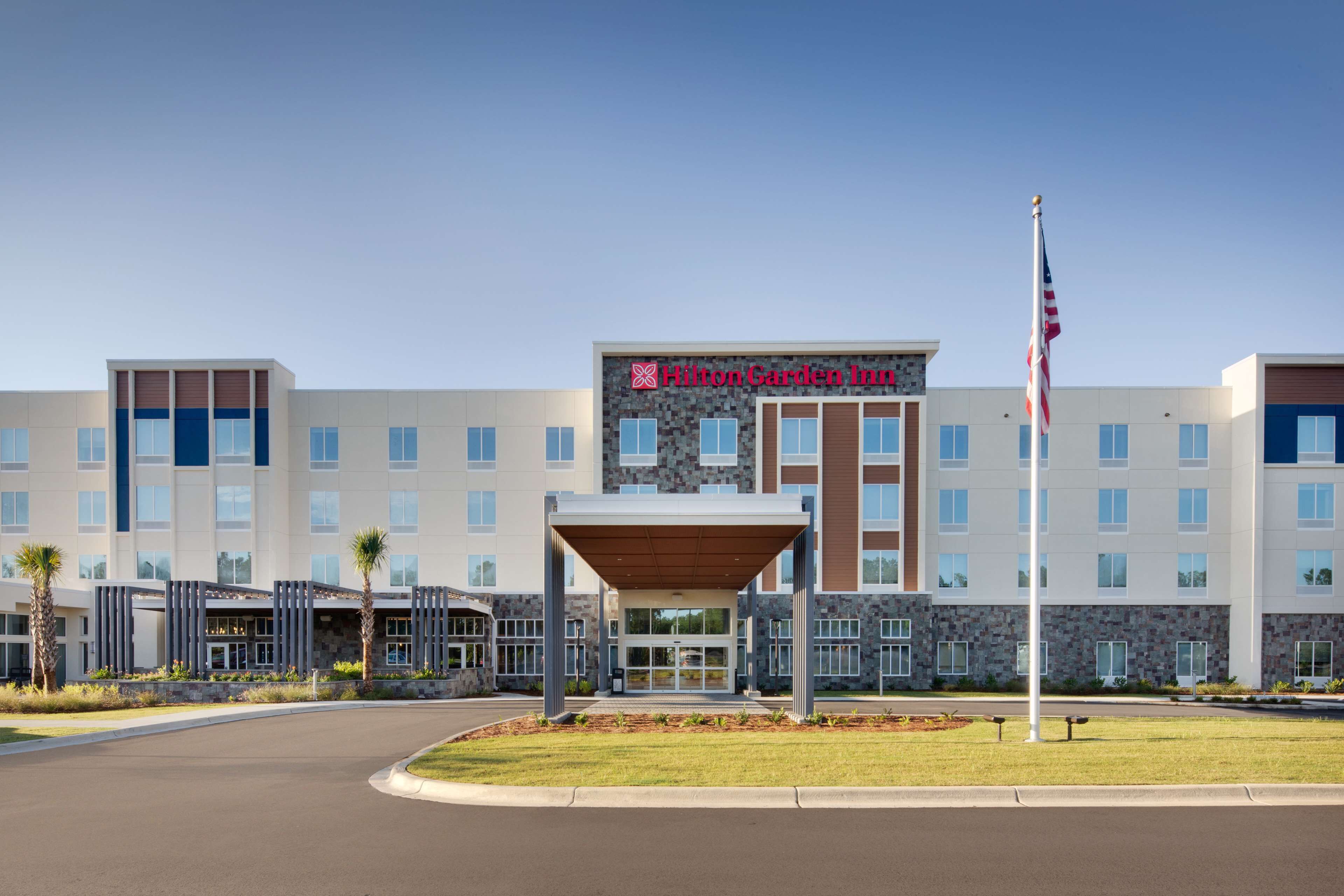 A modern hotel with a prominent entrance, a covered waiting area, and an American flag.