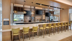 A modern bar area with wooden ceiling, bar stools, and a wine rack.