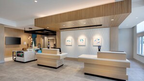 A modern reception area with two reception desks, a mounted TV, and a vending machine.