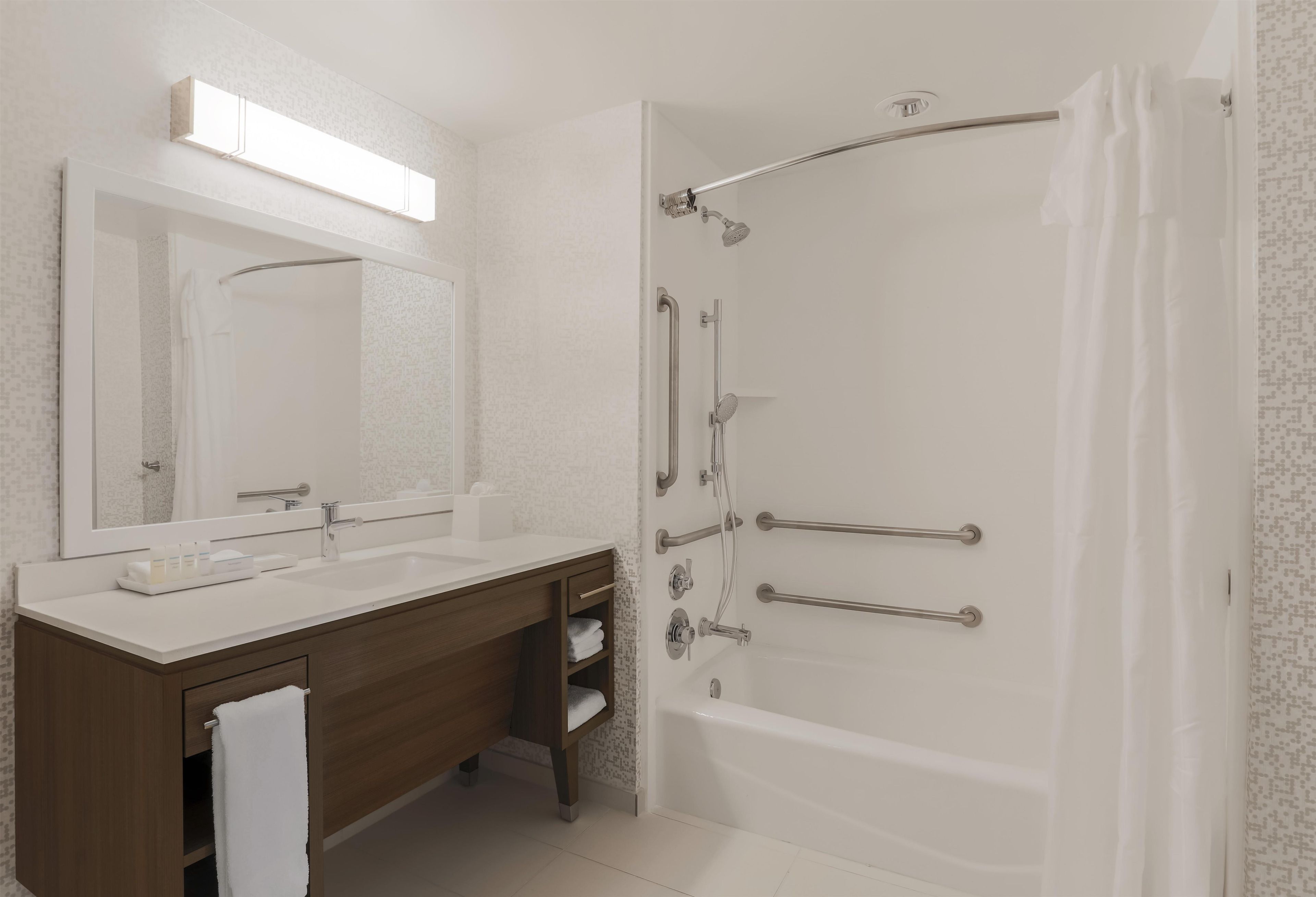 Une salle de bain moderne avec un meuble-lavabo à deux vasques, un grand miroir, une douche avec un pommeau de douche à main et une baignoire.