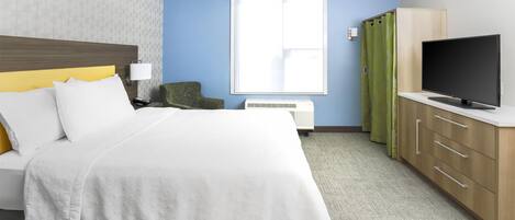 A hotel room with a bed, a TV, a desk, and a window.