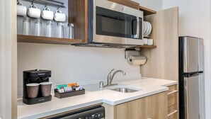 Una cocina moderna con microondas integrado, cafetera y lavavajillas.