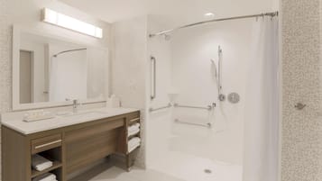 A modern bathroom with a glass-enclosed shower, a wooden vanity with a mirror, and a white sink.