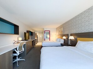 Ein Hotelzimmer mit Bett, Schreibtisch, Stuhl und Fernseher.