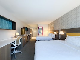 Habitación de hotel con cama, escritorio, silla y televisor.