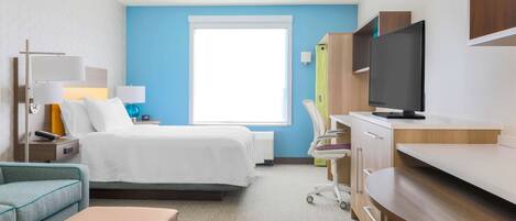 A hotel room with a bed, a desk, a television, a chair, and a nightstand.