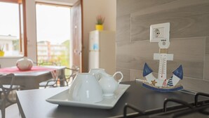 Una encimera de cocina con una tetera blanca y tazas, un pequeño modelo de barco decorativo y un enchufe VIGO.
