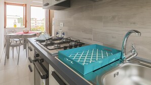 A modern kitchen with a gas stove, a sink, and a dining area with chairs and a table. - Apartment in Capaccio ID 3887 (Licinella-Torre di Paestum)