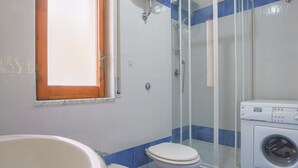 Een badkamer met toilet, bidet en wasmachine.
