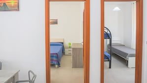 A room with a desk, two beds, a chair, and a painting. - Appartament in Capaccio 4031 (Licinella-Torre di Paestum)
