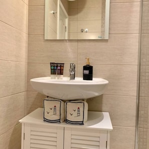A bathroom with a white sink, a mirror above it, and two towels with lighthouse designs on a cabinet below. - Luxury Apartment in Balkan Breeze 7 in Sunny Beach (Sunny Beach)