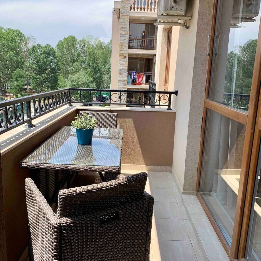 A balcony with wicker furniture, a table, and a potted plant.