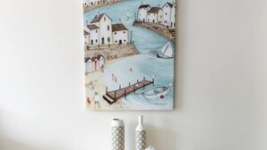 A dining table with a painting of a coastal scene, various dishes, and condiments. - Luxury Apartment in Balkan Breeze 7 in Sunny Beach (Sunny Beach)