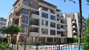 A multi-story residential building with balconies, air conditioning units, and a swimming pool area. - Luxury Apartment in Balkan Breeze 7 in Sunny Beach (Sunny Beach)
