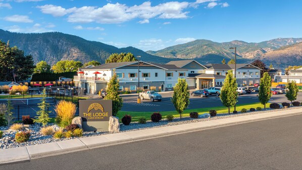 Un hotel con un cartel que dice "The Lodge Lake Chelan", que cuenta con un estacionamiento, una zona de piscina y vistas a las montañas.