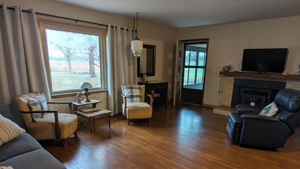 Una sala de estar con sofá, sillones, una mesa de centro, chimenea, televisión y un ventanal grande.