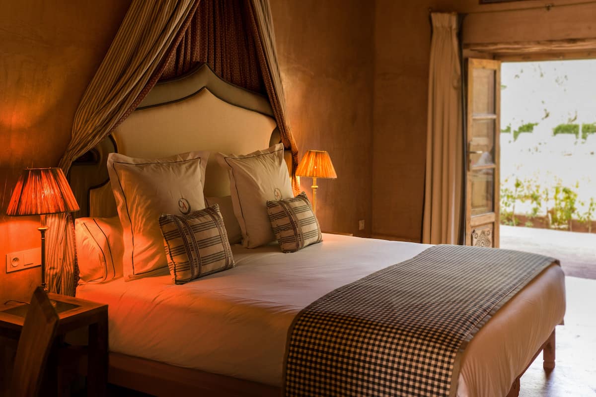 A bed with a canopy, two bedside lamps, and patterned pillows.