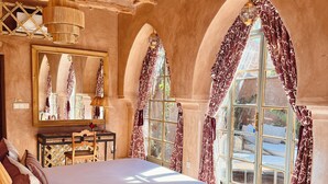 A spacious bedroom with a large bed, a wooden ceiling, and arched windows with patterned curtains. - Casa Abracadabra (Marrakech)