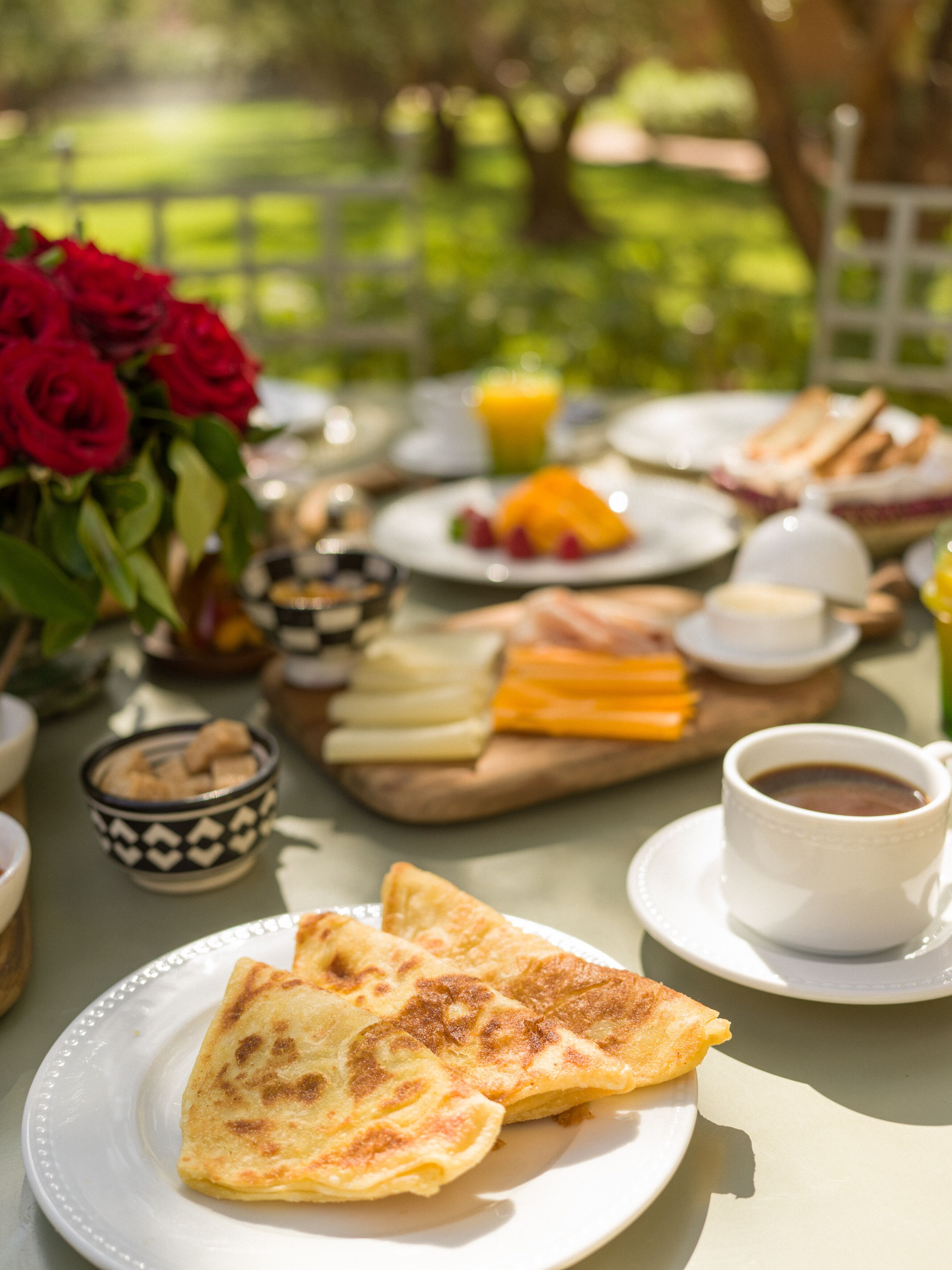 A breakfast setting with a variety of food items including pancakes, fruits, and a cup of coffee.