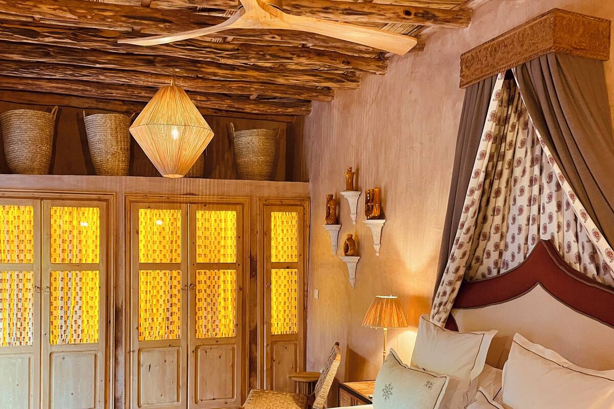 A traditional room with a bed, wooden ceiling, and patterned curtains.