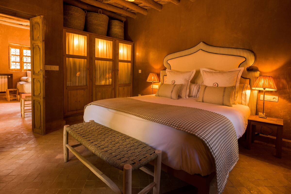 A cozy bedroom with a large bed, wooden headboard, and a bench.