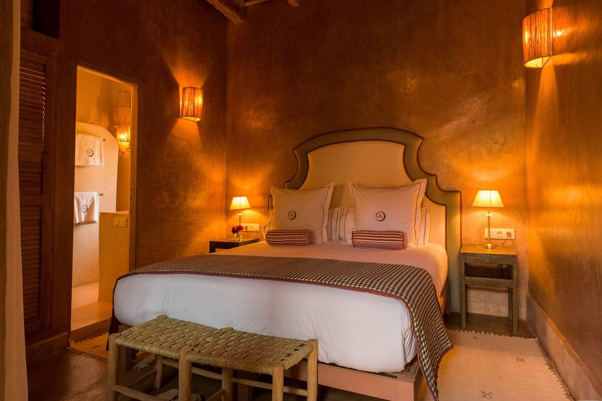 A cozy bedroom with a large bed, two bedside tables with lamps, and a bench at the foot of the bed.