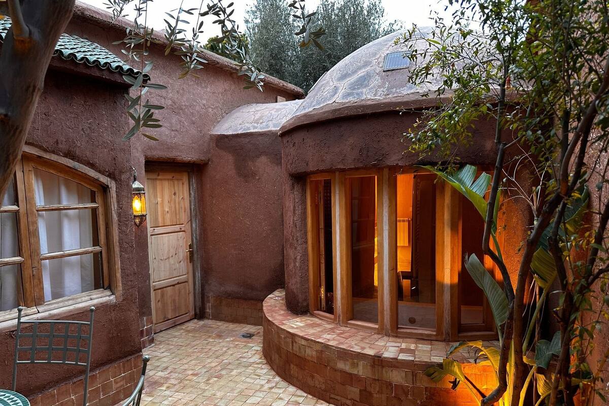 A rustic building with a tiled courtyard, a wooden door, and a window with a metal frame.