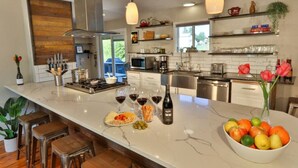 Una cocina moderna con una isla grande, electrodomésticos de acero inoxidable y una variedad de frutas y bebidas.