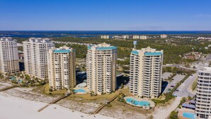A high-rise hotel with multiple balconies, a pool, and a beach view.