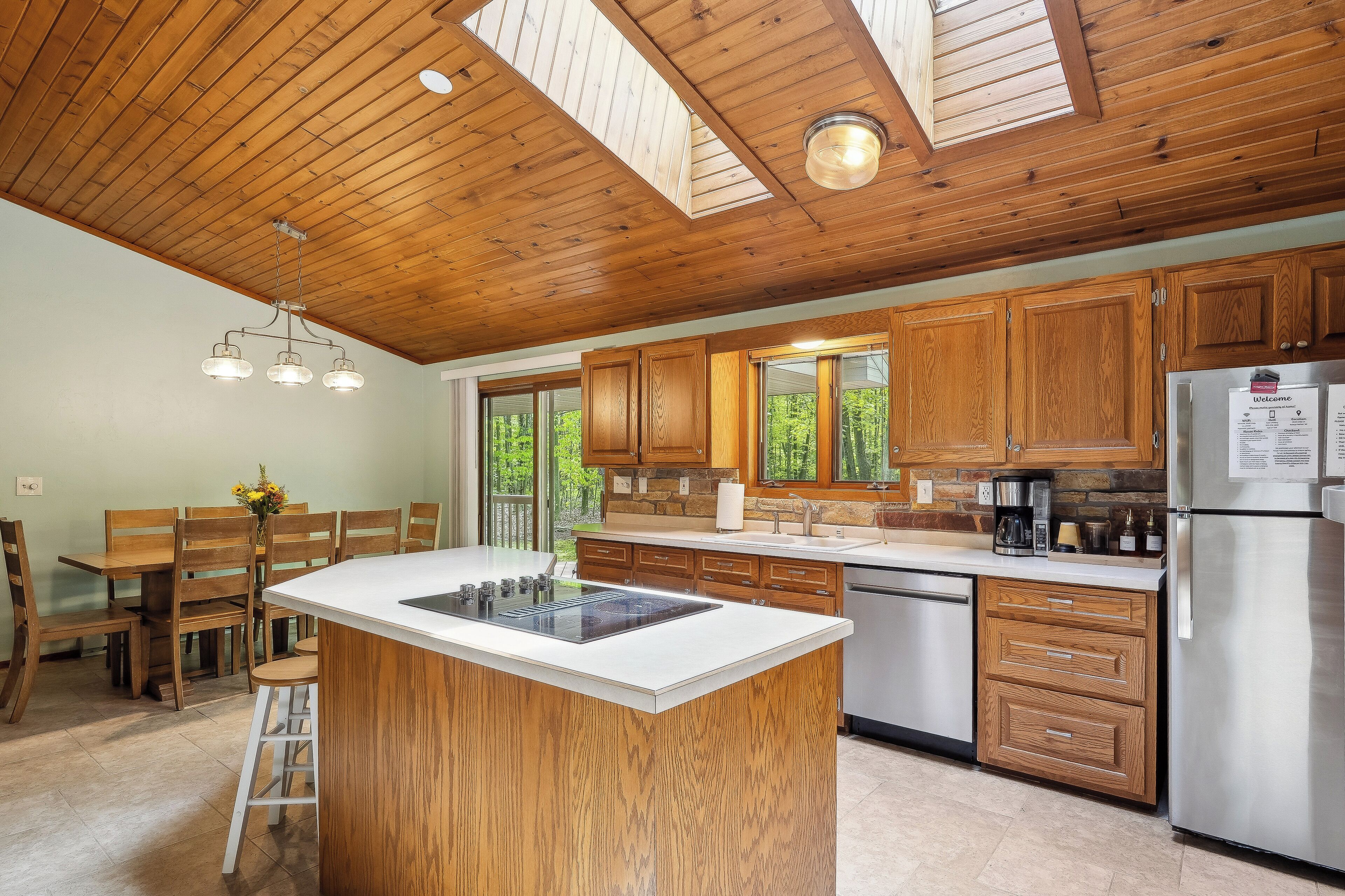 A kitchen with wooden cabinets, a central island, and a stainless steel refrigerator.