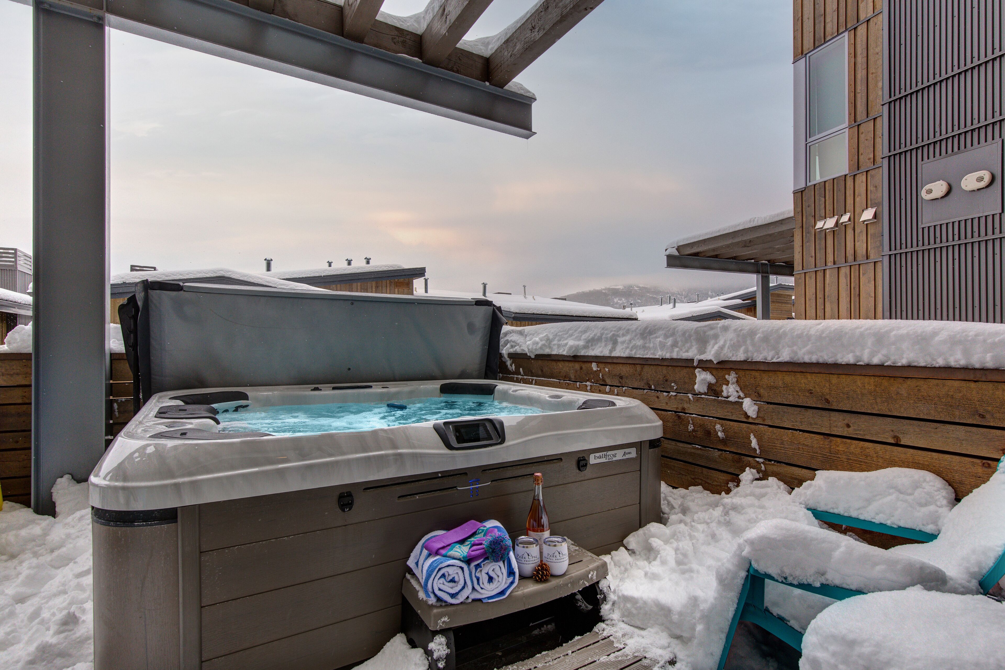 Un bain à remous avec une terrasse en bois et un paysage enneigé.