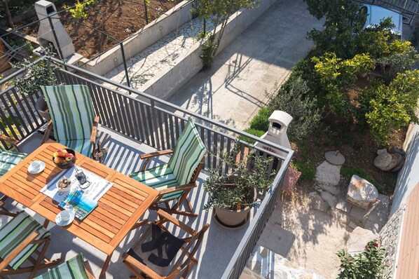 Enjoy dining al fresco on this elevated rooftop terrace with a table set for two, surrounded by lush greenery and a city view.