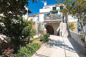Traditional Mediterranean-style building with a stone staircase and lush green surroundings.
