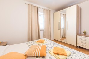 Relax in this serene bedroom with a large bed, floral-patterned bedspread, and a wooden nightstand.