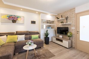 Relax in this stylish living room with a sectional sofa, flat-screen TV, and shelves.