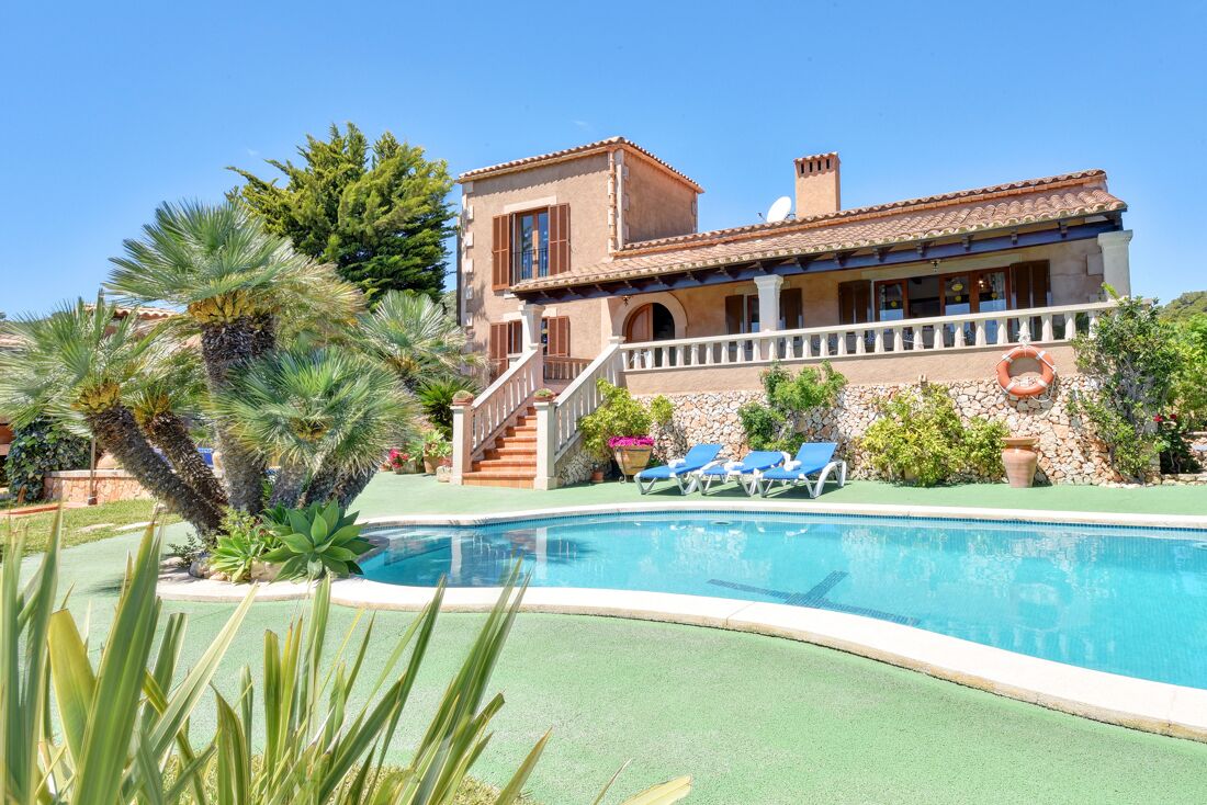 A Mediterranean-style villa with a swimming pool, a covered patio, and a staircase leading to the entrance.
