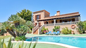 En villa i middelhavsstil med swimmingpool, overdækket terrasse og trappe til indgangen.