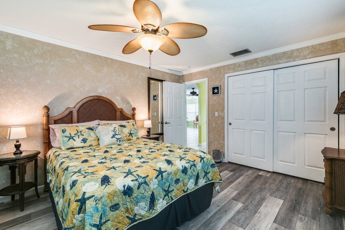 A bedroom with a bed, a ceiling fan, a nightstand, a lamp, and a door with a star sign.