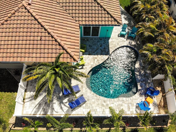 An aerial view of a house with a swimming pool, a tiled roof, and outdoor seating.