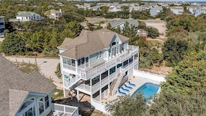 Une maison à plusieurs étages dotée d’un grand balcon et d’une piscine.