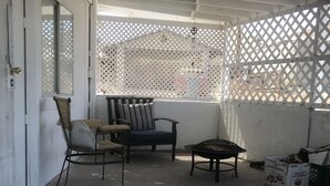 Un espacio de descanso techado al aire libre con una silla, una mesa y una planta en maceta.