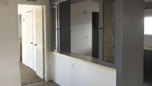 Un pasillo con una puerta blanca, un ventanal con vistas y suelo alfombrado.