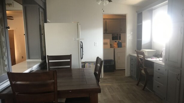 Una cocina funcional con una mesa, sillas, refrigerador y armarios.