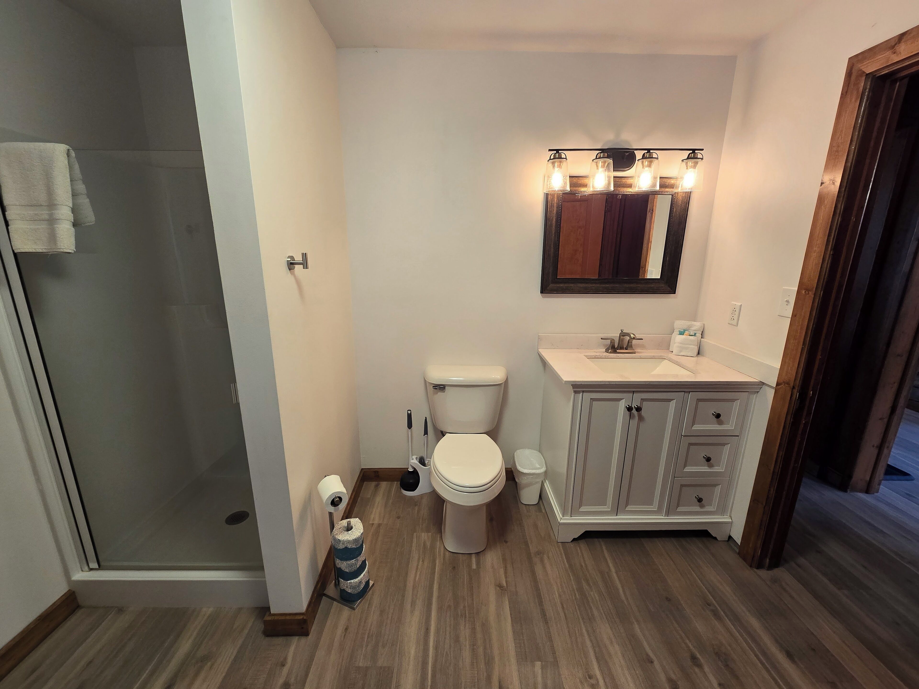A bathroom with a toilet, sink, vanity, and a glass shower enclosure.