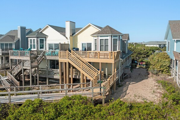 Une propriété située en bord de mer, comprenant plusieurs maisons, une terrasse en bois et une plage de sable.