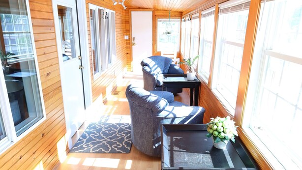 Un interior de madera con un sofá, mesas y ventanas amplias.