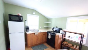 Cocina compacta equipada con refrigerador, microondas, pileta y estufa.