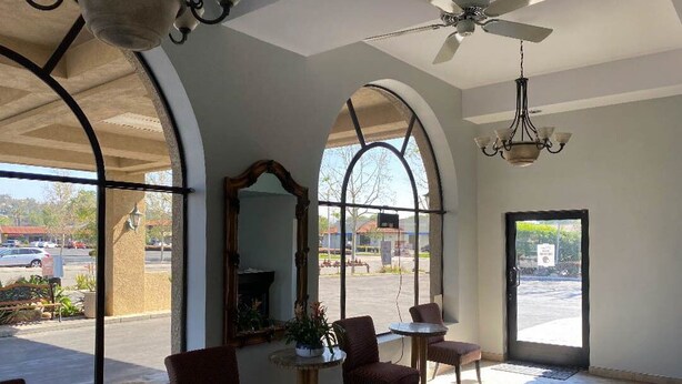 Um hall amplo com janelas em arco, um ventilador de teto e um lustre.