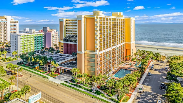 Ein Hotel mit mehreren Stockwerken, einem Pool und Blick auf den Strand.