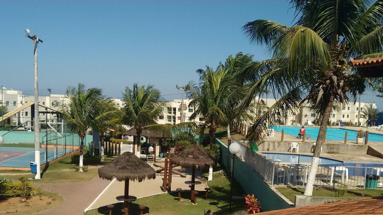 A resort area with a pool, palm trees, and a tennis court.